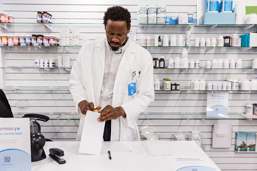 The pharmacist helps package medications that have been filled.