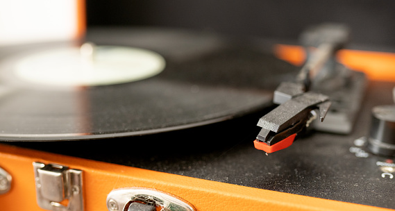 Close-up of an old vinyl record sitting on a dusty portable turntable