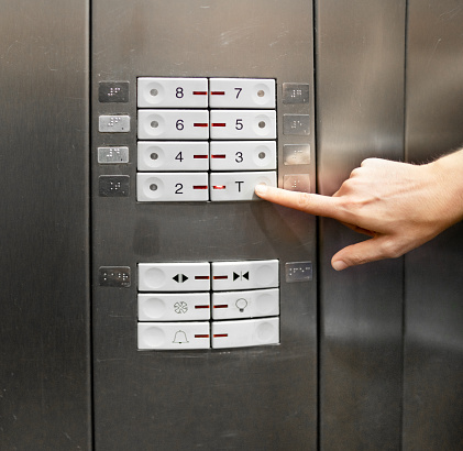 Close-up of a woman's finger pressing a button on the control panel of an elevator