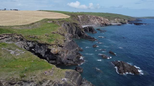 Farm fields on the coast of the Celtic Sea. Landscape of the South of Ireland, West Cork. Picturesque rocks on a sunny day, the nature of Ireland. The area near Clonakilty.
