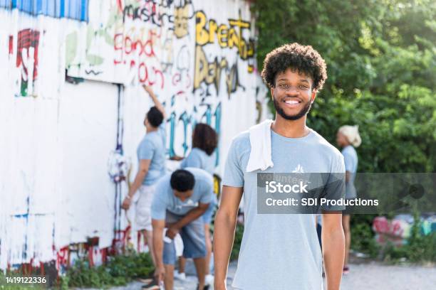 Others Continue Painting Over Graffiti As Student Smiles For Camera Stock Photo - Download Image Now