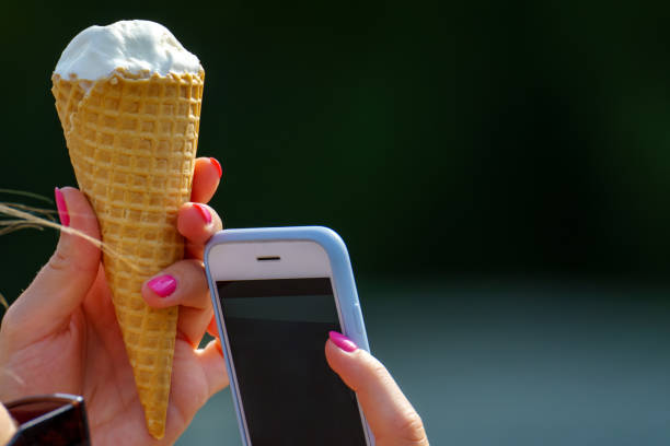 um telefone grande e sorvete em um cone de waffle são mostrados - blue blueberry cold food descriptive color - fotografias e filmes do acervo