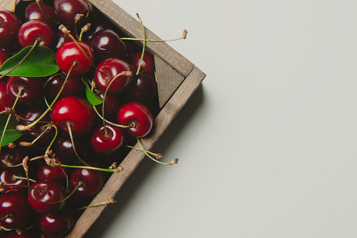 Fresh cherries in a wood container on the white background.