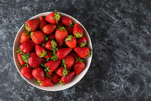 Fresh strawberries in a bowl on wooden kitchen table