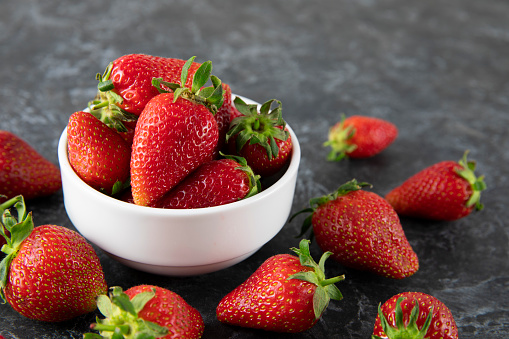 Fresh strawberries in a bowl on wooden kitchen table
