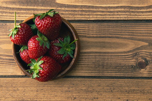 Fresh ripe strawberries in a the wooden bowl.