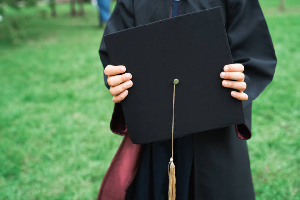 retour au concept de l’école primaire. la petite fille va en première année. cérémonie d’obtention du diplôme. robe noire, casquette académique avec glands. fête avec les parents, les enseignants dans le parc, la cour. dernier jour, fin d’ann - fête de lécole photos et images de collection