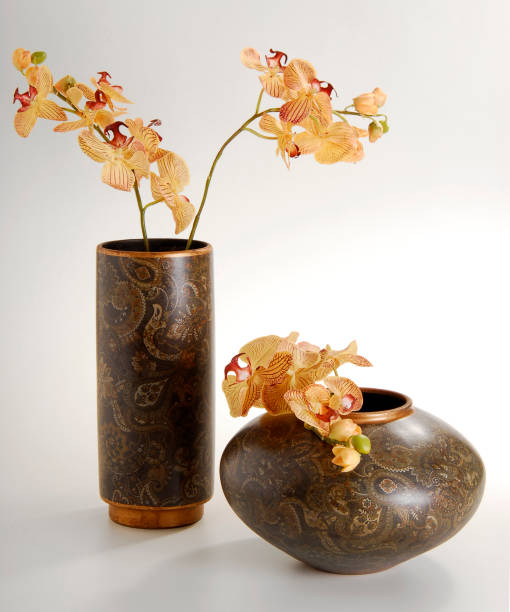 istock Two brown vases with paisley pattern, one tall and the other round, with orchids inside, isolated on white 1419130819