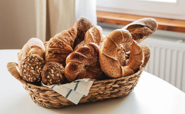 petit déjeuner - panier rustique avec différents types de petits pains sur la table à la maison - country bread photos et images de collection