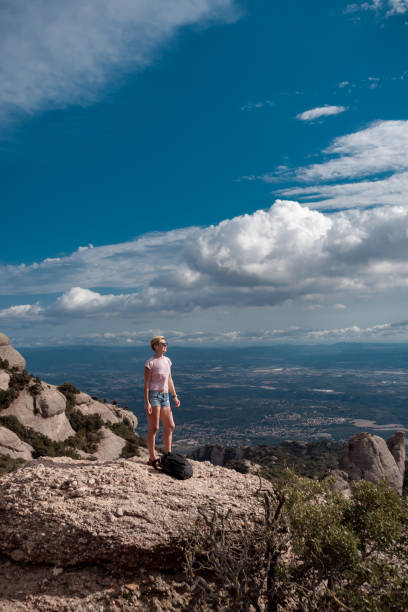 Shot of female hiker on top of Montserrat mountain in Spain. Traveler woman standing on a stone looking at the view. stock photo