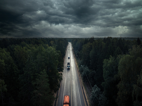 Dark dramatic overcast sky over the multiple lane highway through the forest, calm before storm