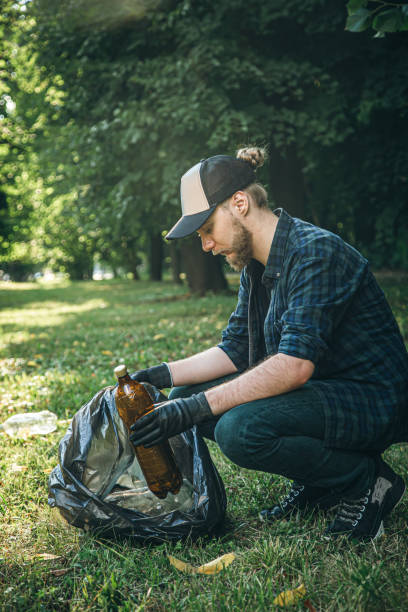 istock A young man with a trash bag in the forest cleans up plastic bottles. 1419136644