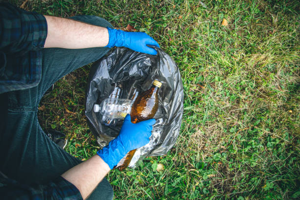 istock A man cleans up the forest, throws a bottle into a trash bag, close-up. 1419136676