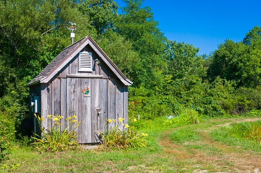 beautiful wooden professionally repaired outhouse in a green forest serves as a toilet in nature on sunny day