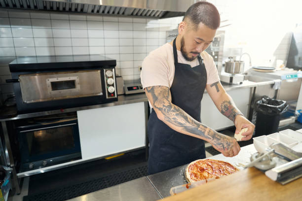 istock Concentrated chef putting grated cheese on top of pizza 1419139050