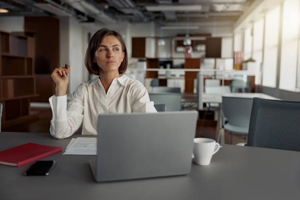 istock Focused european business woman working laptop and making notes while sitting in modern office 1419139498