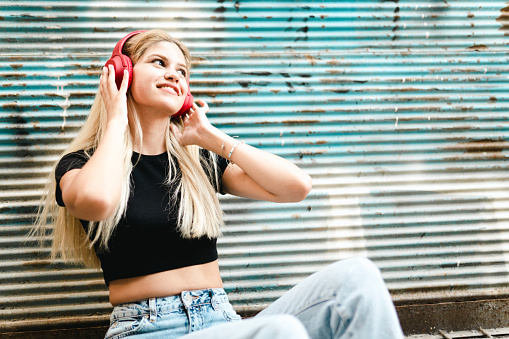Portrait of a happy young woman listening to music in the city