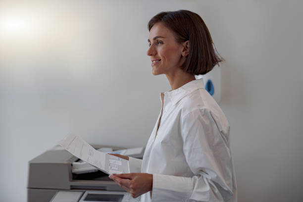 istock Smiling woman worker scanning a document on photocopy machine In modern office 1419139787