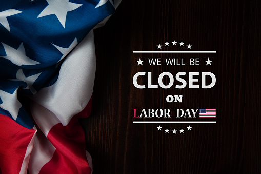 Labor Day Background Design. American flag on a wooden table with a message. We will be Closed on Labor Day.