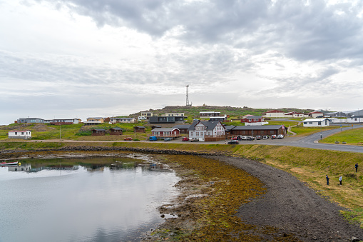 Djupivogur, Iceland - 26 july, 2021; Town at fjord Berufjörður, traditional houses at the coast, some people cleaning the grass at the beach. Eastern Iceland