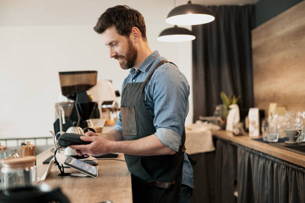 istock Smiling barista holds a payment terminal in his hands 1419141515