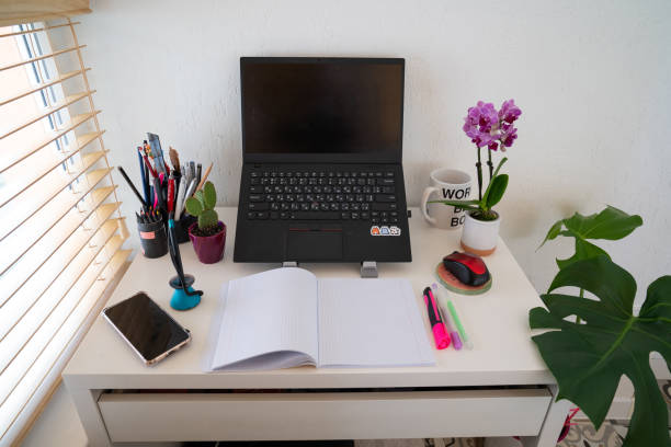 istock cozy modern workplace, space, home office: table desk with laptop, computer mouse, stationery, orchid plant, cup, open textbook with white pages, pen. Concept of work from home, study, back to school 1419143961