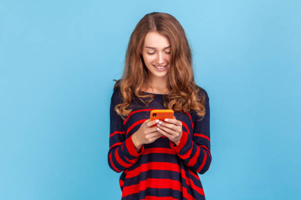 istock Woman with pleasant smile using cell phone, answering messages in social networks, writing post. 1419144065