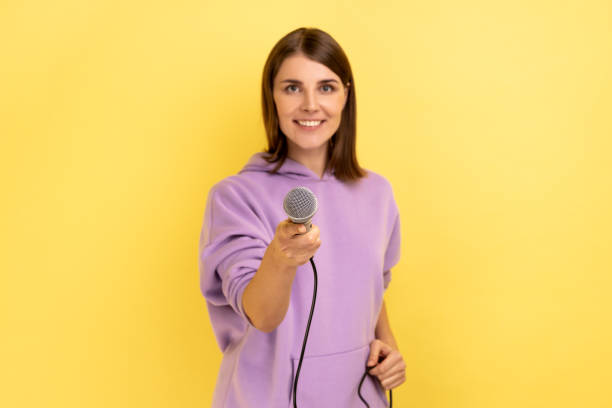 istock Delighted woman with dark hair standing offering microphone, journalist taking interview. 1419144213