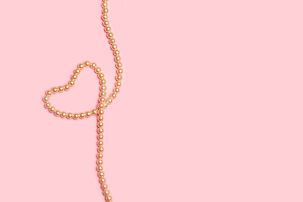 istock Heart shape made with a pearl necklace on a pink background 1419144496