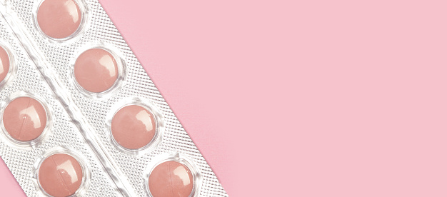 Medical pills in a blister on a pink background with copy space
