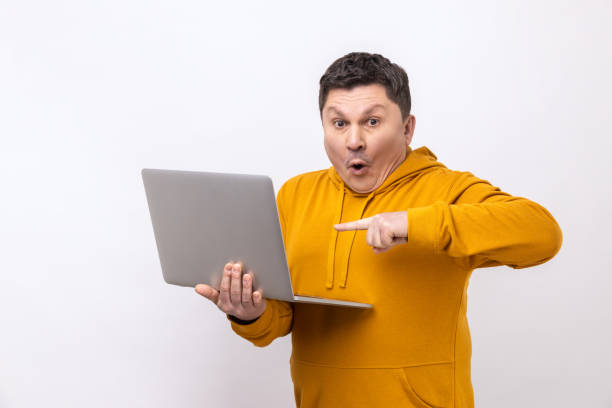 istock Astonished man working on laptop typing email or chatting in social network, pointing at display. 1419145771