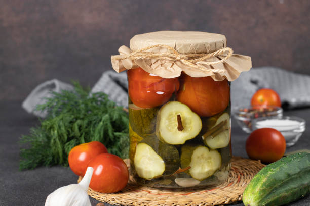 istock Pickled cucumbers with cherry tomatoes in jar on brown background with fresh ingredients 1419149397