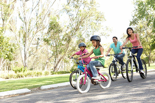 jeune famille équitation vélos dans un parc - family bicycle cycling healthy lifestyle photos et images de collection