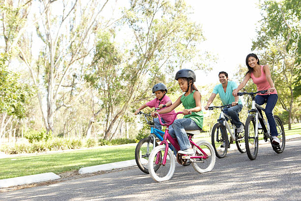 młoda rodzina jeździ rowery w parku - amusement park ride zdjęcia i obrazy z banku zdjęć