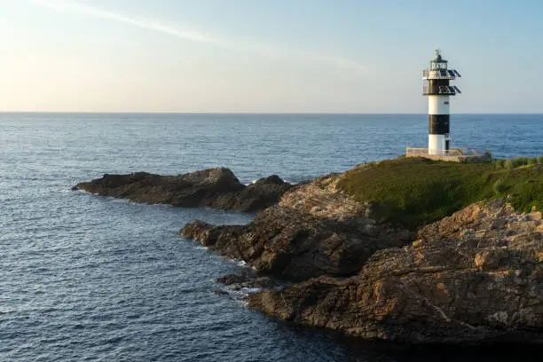 Photo of Pancha island lighthouse at sunset in Ribadeo coast, Lugo province, Galicia, Spain