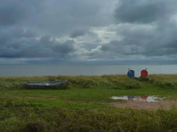 Photo of Seascape with Weathered Rowboat and Improvised Acadian Flag, New Brunswick, Canada