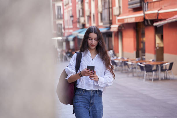 istock young woman walking using a cellphone in the street 1419155215