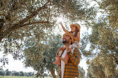 Father with small daughter walking outdoors by olive tree