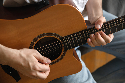 Young man playing an acoustic guitar at home