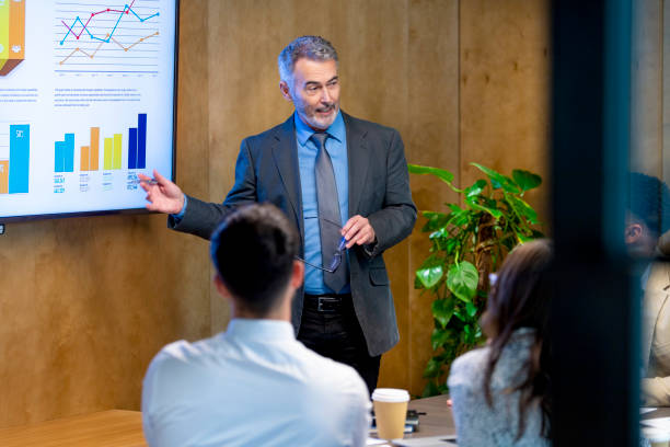 istock Mature man giving a big data presentation on a tv in a board room. 1419159359