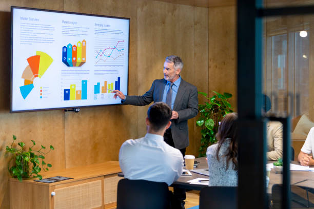 istock Mature man giving a big data presentation on a tv in a board room 1419159361