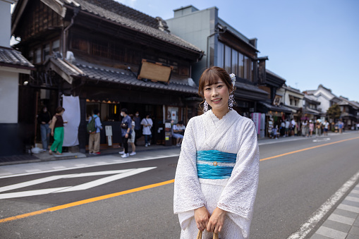 Japanese woman visiting traditional Japanese town. Renting a white lace kimono, eating Japanese food and shopping in retro style Japanese stores, etc.