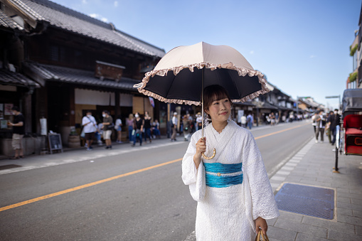 Japanese woman visiting traditional Japanese town. Renting a white lace kimono, eating Japanese food and shopping in retro style Japanese stores, etc.