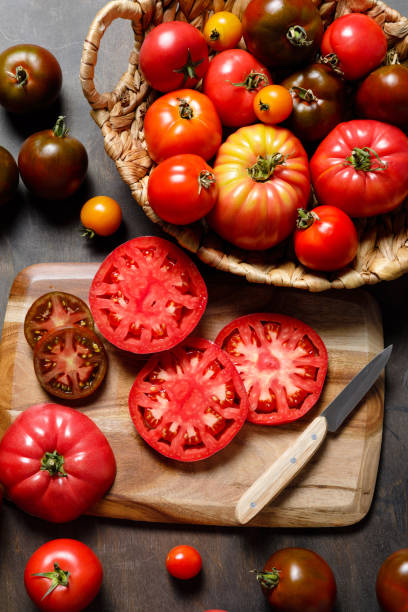 fresco colorido outono maduro ou tomates de variedade de herança de verão com faca e tábua de cortar sobre fundo de mesa de madeira. conceito de molho de tomate de colheita e cozimento - heirloom tomato organic tomato rustic - fotografias e filmes do acervo