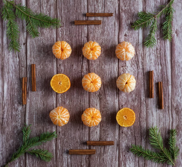 Orange tangerine or mandarins with green branches of Christmas tree and cinnamon sticks on wooden background. Christmas and New Year concept