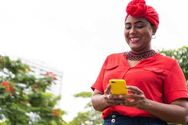 istock Happy trendy Afro woman using smartphone and smiling on park 1419173799