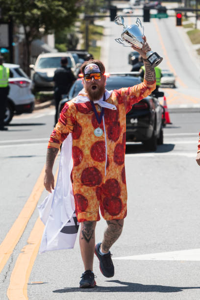 l'uomo che indossa il costume della pizza solleva il trofeo dalla vittoria della corsa del letto - humor athlete trophy one person foto e immagini stock