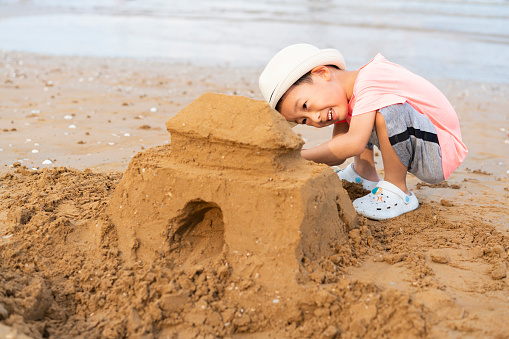 A baby digging sand by the sea