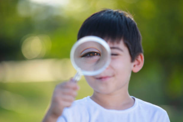 istock cute and curious little boy looking through a magnifying glass 1419181292