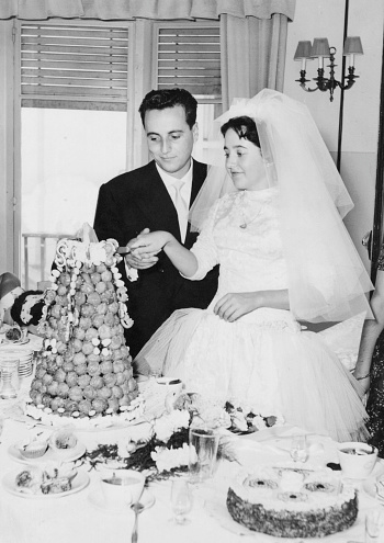 Vintage image from the 50s : Young couple posing cutting their wedding cake